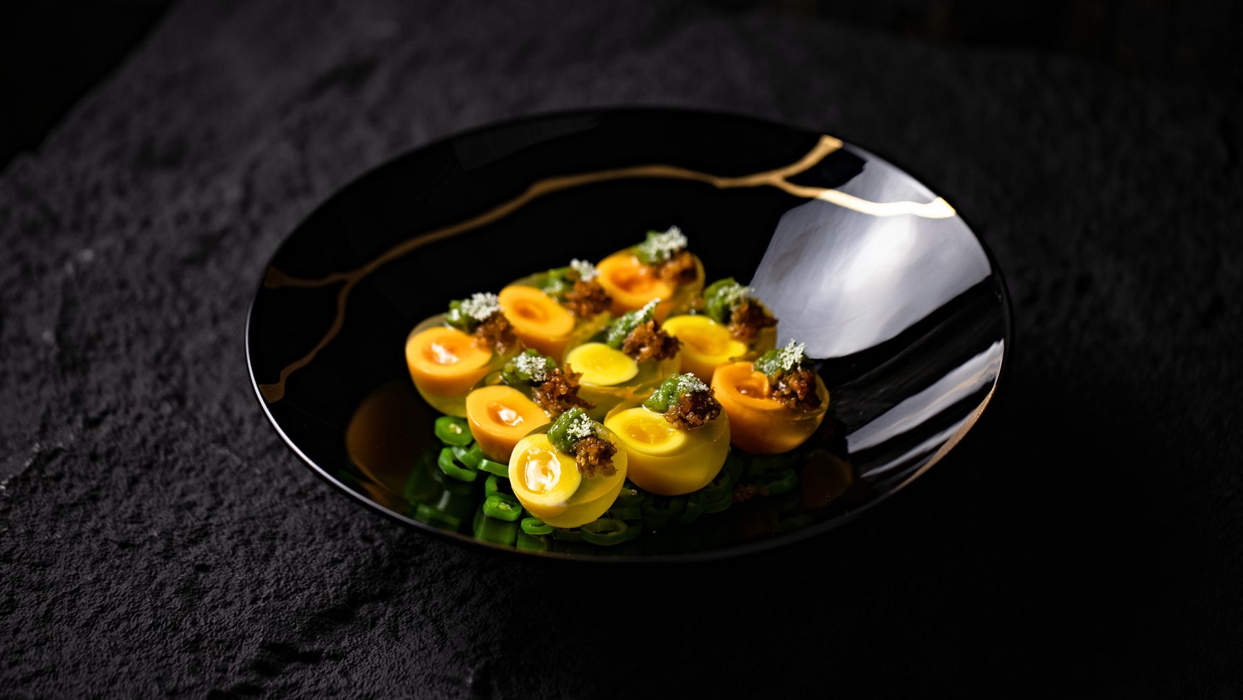 Fine-dining course under a single spotlight on a dark table