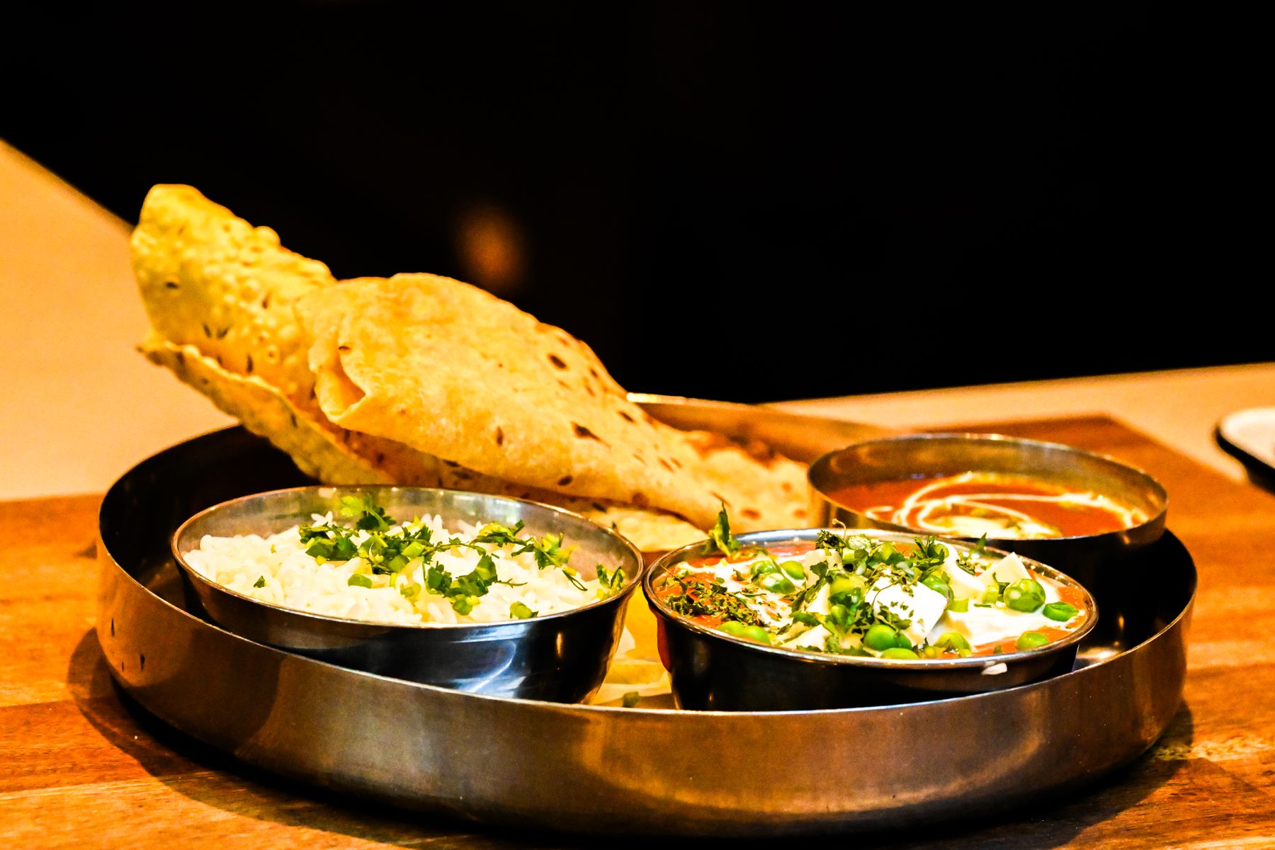 Traditional Indian thali with breads and curries in warm light